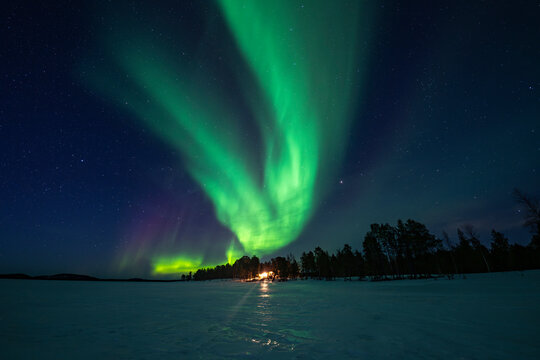 Northern lights over frozen lake and forest in Finland