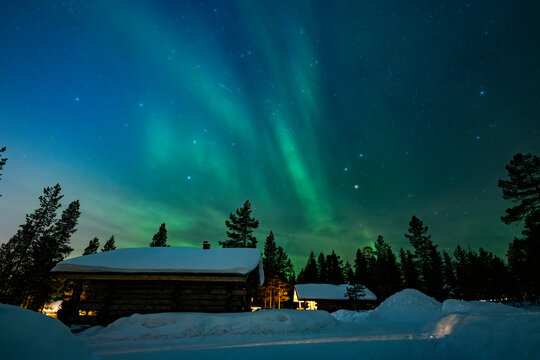 Northern lights over snowy cabin forest in Finland night