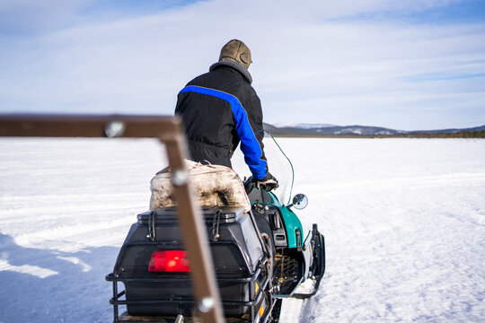 Snowmobile rider crossing a frozen lake in Finland