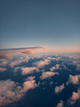 Airplane wing above winter clouds and sea at sunset