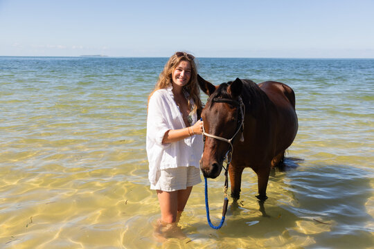 smiling young boy posing with horse at edge of ocean,Mozambique, Africa