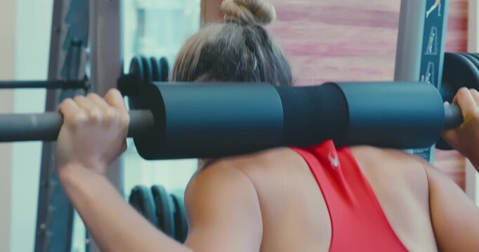 Woman Performing Squats in Gym with Smith Machine