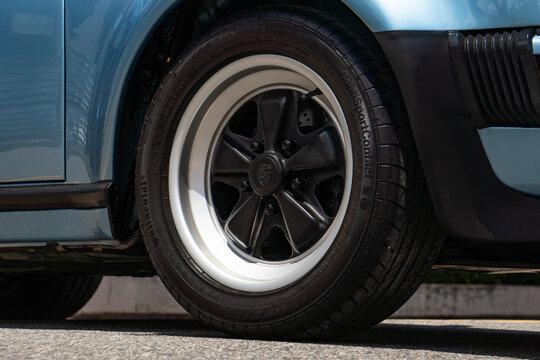 Blue Porsche 930 Turbo front wheel and fender, Classic sports car rim closeup on asphalt
