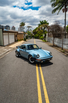 Blue Porsche 930 high angle front three quarters view, Classic sports car on city street wide shot