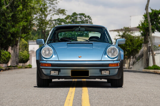 Blue Porsche 930 Turbo front view centered outdoors, Classic sports car on city road