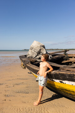 10 year old boy leaning on old fishing boat, Vilankulos, Mozambique, Africa