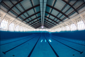 Obraz premium Indoor swimming pool with deep blue water, showing modern architecture and lanes for competitive swimming