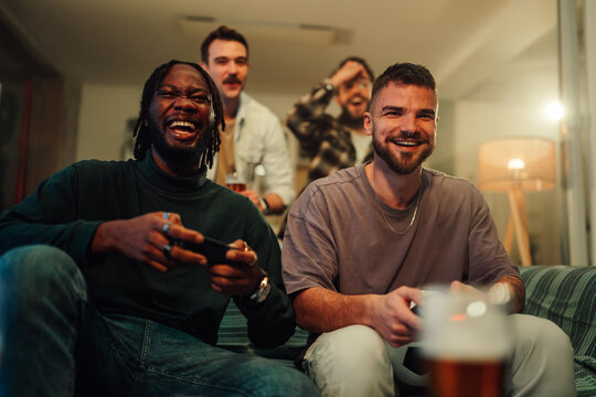 Young men enjoying gaming party home playing online video games laughing having fun and drinking beer