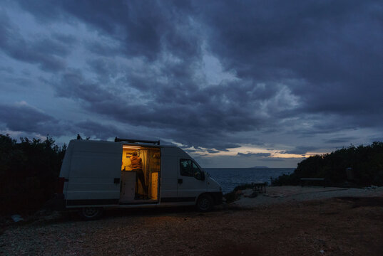 Camper van besides gravel road on the Adriatic Sea coast preparing for the night during blue hour in the evening, Himare, Albania