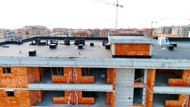 Close up aerial view of flat roof construction with waterproofing. Close up of building roof under construction with orange brick walls and bitumen waterproofing rolls.