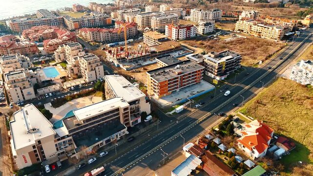 High angle view of coastal resort town with infrastructure. Wide aerial perspective of a coastal town showing roads, residential complexes, and ongoing construction.