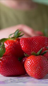 Child's Hand Picking Strawberries One by One from Stacked Pile &mdash; Boy Taking Fresh Summer Berries from Pyramid Stack, Ground Level Close-Up, Healthy Snacking Concept Vertical