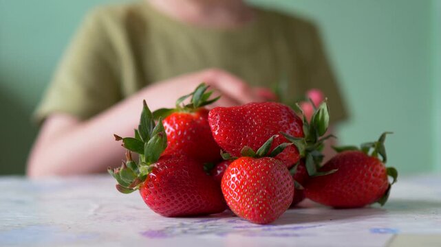 Child's Hand Picking Strawberries One by One from Stacked Pile &mdash; Boy Taking Fresh Summer Berries from Pyramid Stack, Ground Level Close-Up, Healthy Snacking Concept