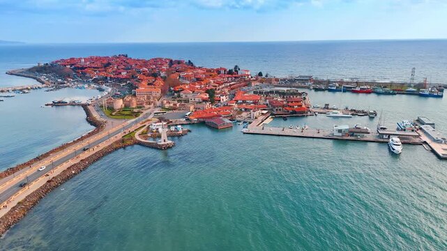 Panoramic aerial view of ancient seaside town peninsula. Wide drone shot of a historic town on a peninsula connected by an isthmus to the mainland.