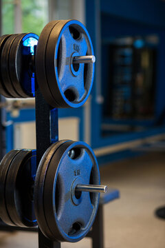 Stacked weight plates on gym rack with 10kg marking and shallow depth of field in fitness center