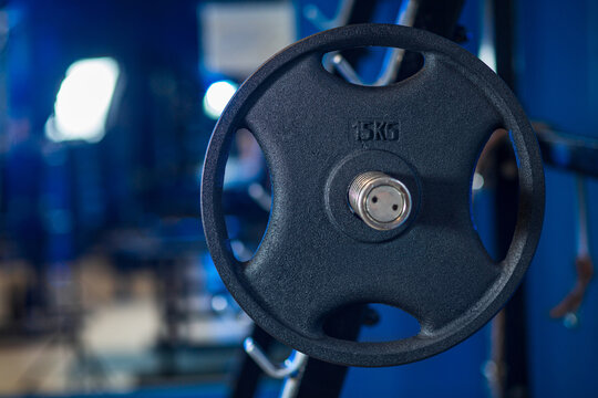 Weight plate with 15kg marking on gym equipment with shallow focus and blue toned lighting