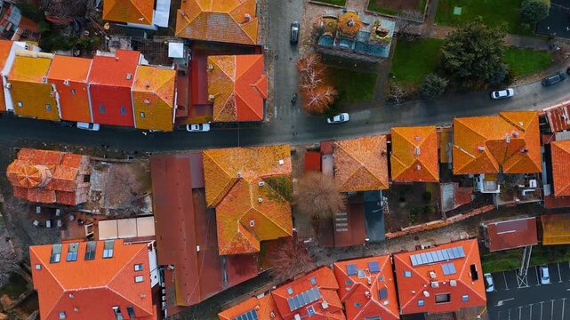 Top down view of traditional red tiled rooftops. Bird's eye view of narrow streets and houses with orange tile roofs.