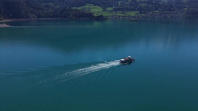 Drone performing a partial orbit around a passenger ferry on an alpine lake in Switzerland, revealing dynamic movement and scenic surroundings.