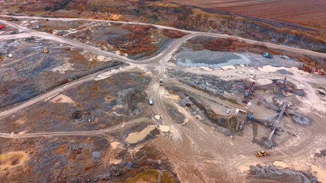 Aerial view of industrial stone processing plant and conveyor belts. Drone shot of a quarry site showing machinery, sorting systems, stockpiles of gravel, and transport trucks.