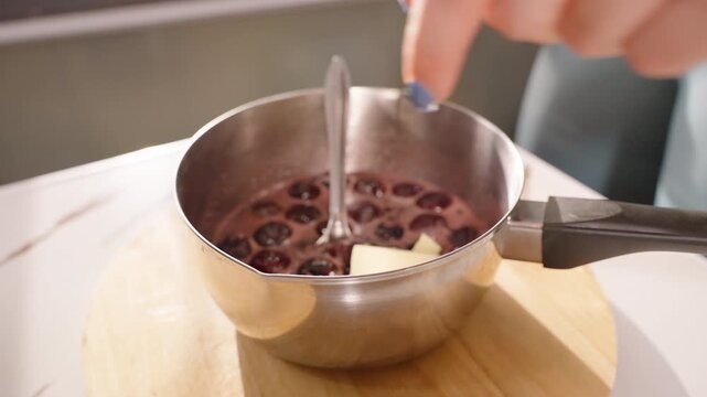 Close Up Hand Adding Cubes of Butter into Hot Cherry Mixture in Saucepan with Steam Rising, Slow Motion, Dessert Preparation Concept