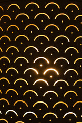 Fototapeta premium Golden light creating a repeating abstract pattern with glowing semicircles and dots on a dark background