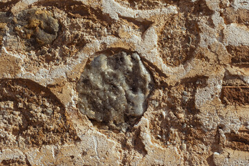 Obraz premium Close-up view of an old rugged stone wall, showing weathered texture, mortar, and a large round grey stone