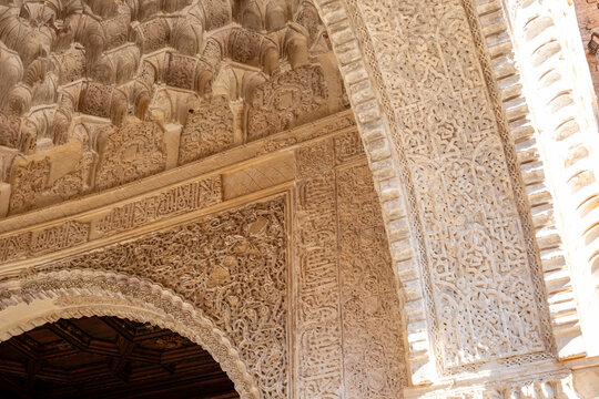 Alhambra intricate plasterwork detail, exploring moorish geometric patterns, arabic calligraphy, and stucco ornamentation