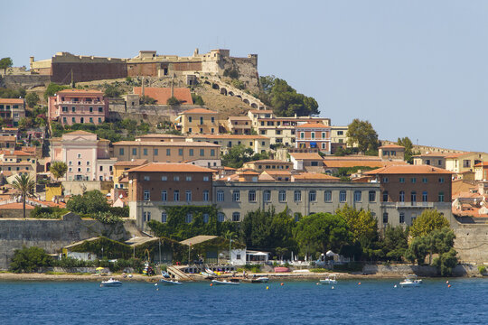 View of the vibrant town cascading down the hillside towards the shimmering sea, with historic buildings and terracotta roofs, Portoferraio, Tuscany, Italy.