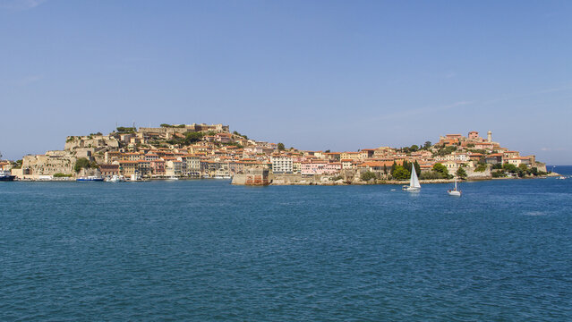 View of the historic city nestled along the coast with terracotta rooftops and ancient walls, contrasting with the shimmering turquoise sea, Portoferraio, Elba, Tuscany, Italy.