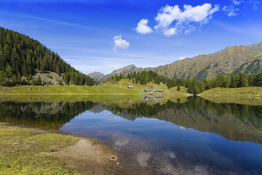 View of the serene Duisitzkarsee lake reflects the surrounding verdant alpine slopes and the clear blue sky dotted with fluffy clouds, Duisitzkarsee, Styria, Austria.
