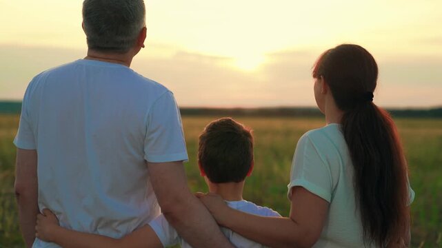 Family unity at sunset father mother son. Child son, dad mom hug against backdrop nature sunset. Family in park kid hug parents in sunny meadow. Father mother child. Family children weekend in nature