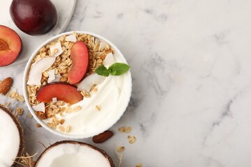 Fototapeta premium Delicious coconut yogurt with granola and plum in bowl on light marble table, flat lay. Space for text