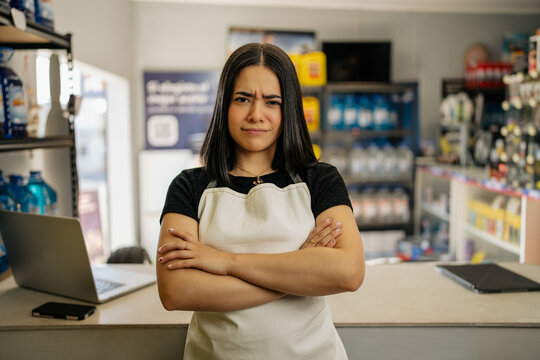 Young woman employee in apron with crossed arms showing an annoyed face