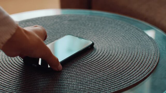 A smartphone is placed on a round woven table mat in a warm indoor environment. The soft surface complements the sleek design of the device. Natural light enhances the scene.
