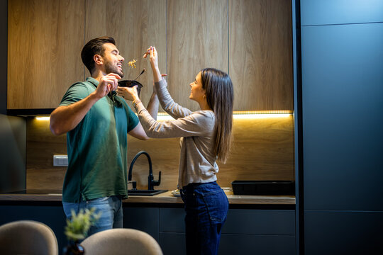 Playful young couple having fun with food while cooking in the kitchen.