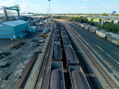 Aerial view of large-scale industrial coal export terminal featuring loaded hopper cars on parallel rail tracks and heavy processing infrastructure.