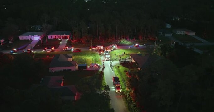 Fire engine trucks and ambulance vehicles responding to fire alarm at night. Investigation of carbon monoxide gas hazard at private house in USA.