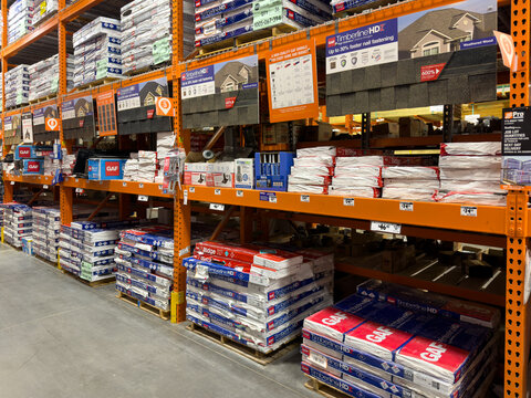 Prosper, Texas, USA - April 1st, 2026: Large pallets of GAF Timberline HDZ architectural roofing shingles stacked on orange metal storage racks in The Home Depot