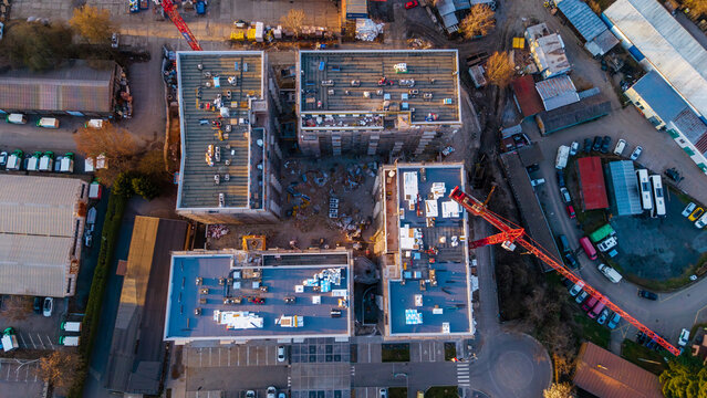 Aerial view of construction site with red cranes piercing the skyline, buildings rising against the urban sprawl, Prague 9, Prague, Czechia.