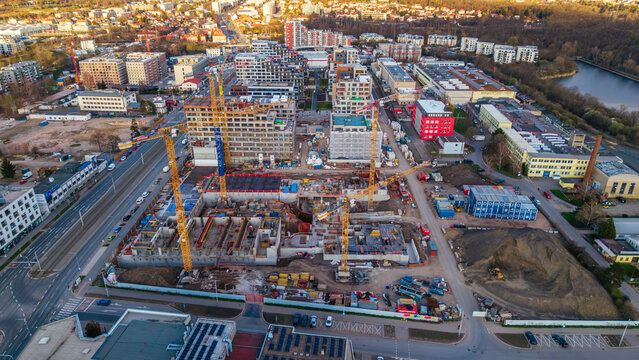 Aerial view of a construction site with towering cranes against a backdrop of buildings and river, Prague 9, Prague, Czechia.