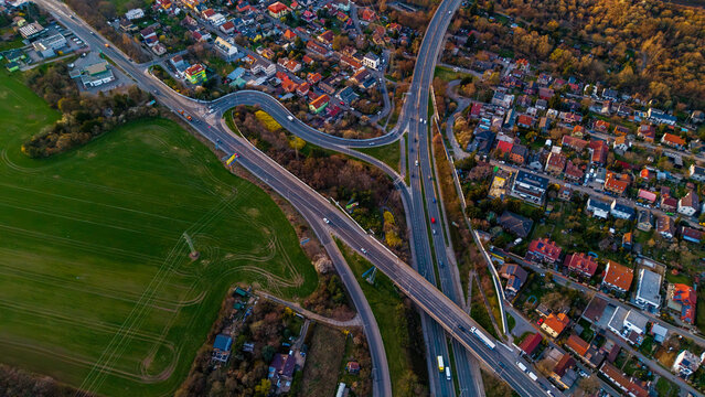 Aerial view of roads cutting through green fields, and homes casting long shadows in the golden light, Praha, Hlavni mesto Praha, Czechia.