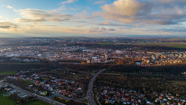 Aerial view of a sprawling cityscape where the urban fabric meets verdant outskirts under a sky streaked with golden light, Praha, Hlavni mesto Praha, Czechia.