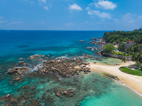 Aerial view of the turquoise waters meeting the rocky coastline, a tropical haven bathed in sunlight, Vista do Mar, Mahe island, Seychelles.