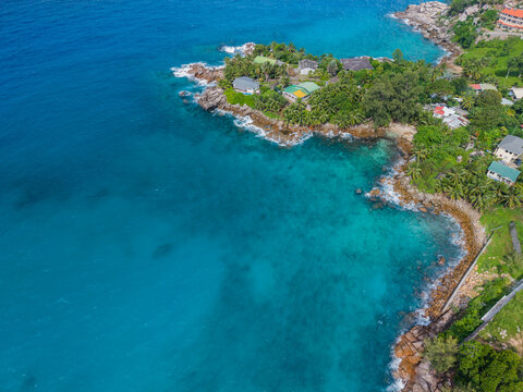 Aerial view of the rugged coastline where turquoise waters meet the verdant land, creating a stunning contrast of colors and textures, Vista do Mar, Mahe Island, Seychelles.
