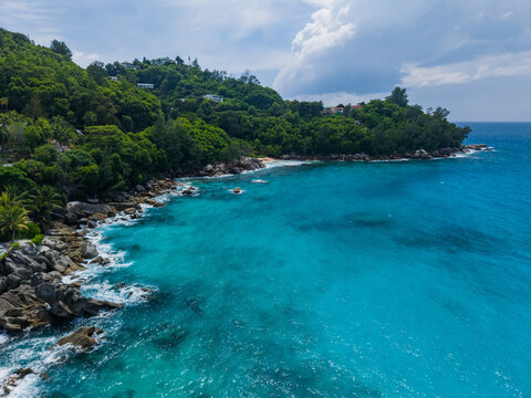 Aerial view of the turquoise sea meeting the rugged coastline, lush green hills rolling down to the shore, Vista do Mar, Mahe Island, Seychelles.
