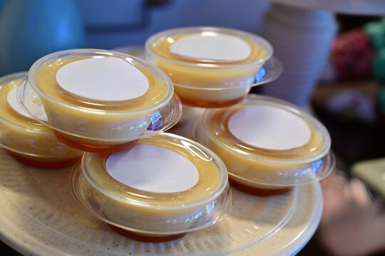 individual caramel flan portions in plastic cups, traditional brazilian pudim de leite condenseado for party, sweet custard dessert with caramel sauce in takeout packaging, group of mini flans 