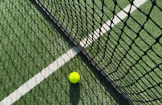 Ball Beside Tennis or Padel Net on Green Artificial Turf Court with White Line, Outdoor Sports Background with Copy Space