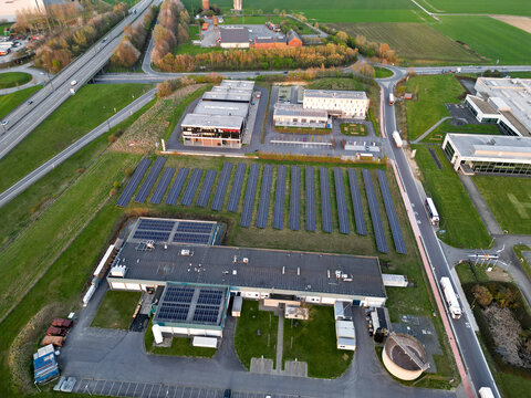Aerial view of industrial buildings and solar panels basking in the soft glow of the setting sun, Ath, Wallonia, Belgium.