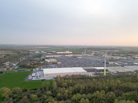 Aerial view of a vast industrial landscape dotted with wind turbines, contrasting the pale structures against the surrounding verdant fields, Ath, Wallonia, Belgium.