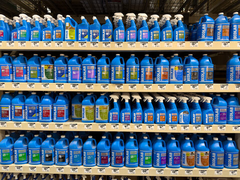 Prosper, Texas, USA - April 1st, 2026: Rows of various blue Ecolab commercial cleaning chemical spray and pour bottles stacked on metal wire shelving in The Home Depot
